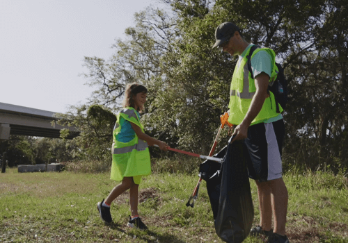 father and daughter wearing high visibility vests and cleaning up the bradenton area
