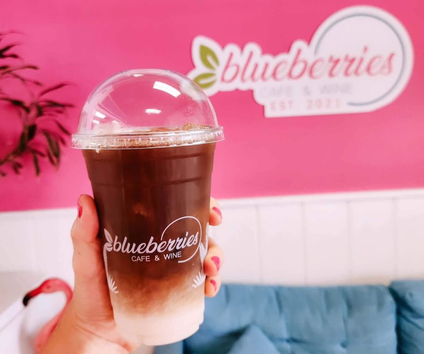 Bradenton Area Coffee Spots person holding iced coffee with Blueberries Cafe Logo on it