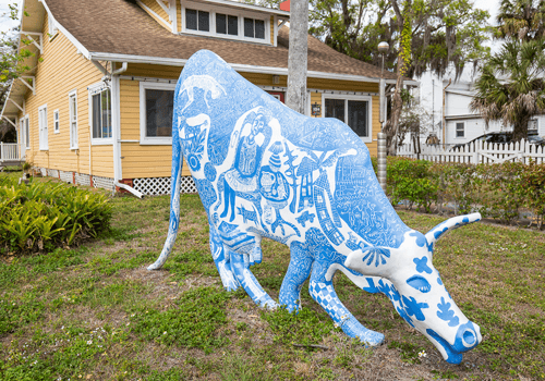 blue and white painted cow sculpture in a yard in village of the arts
