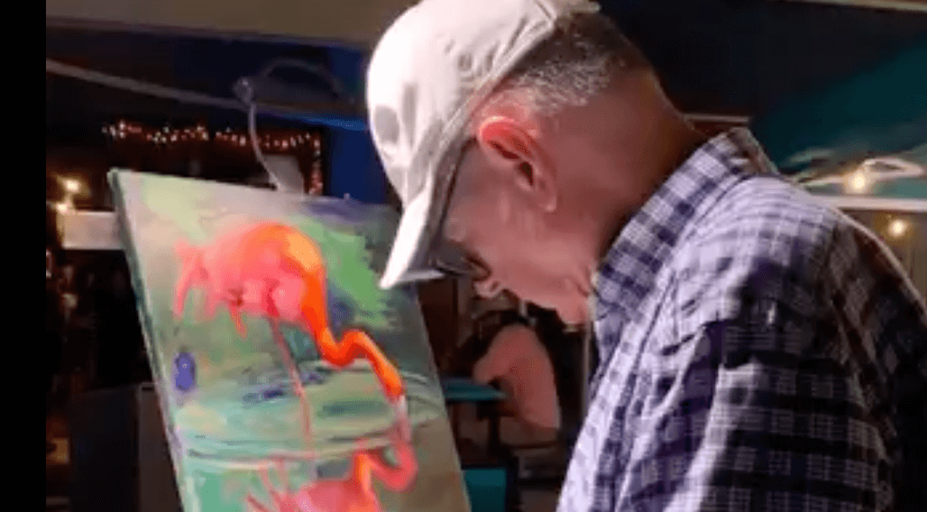 Picture of Daryl Goldman with Flamingo painting to be raffled.