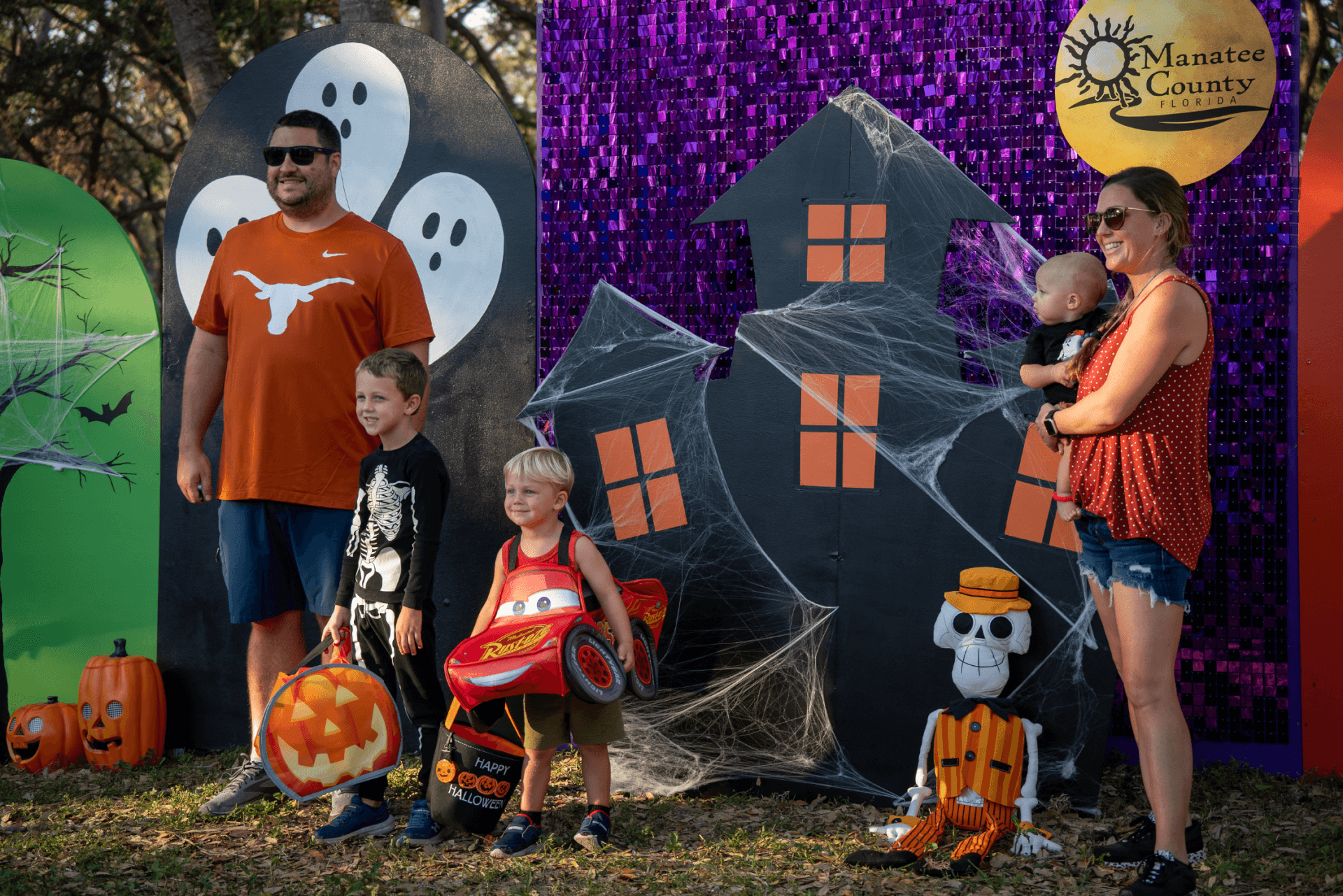 Family posing at Halloween-themed backdrop.