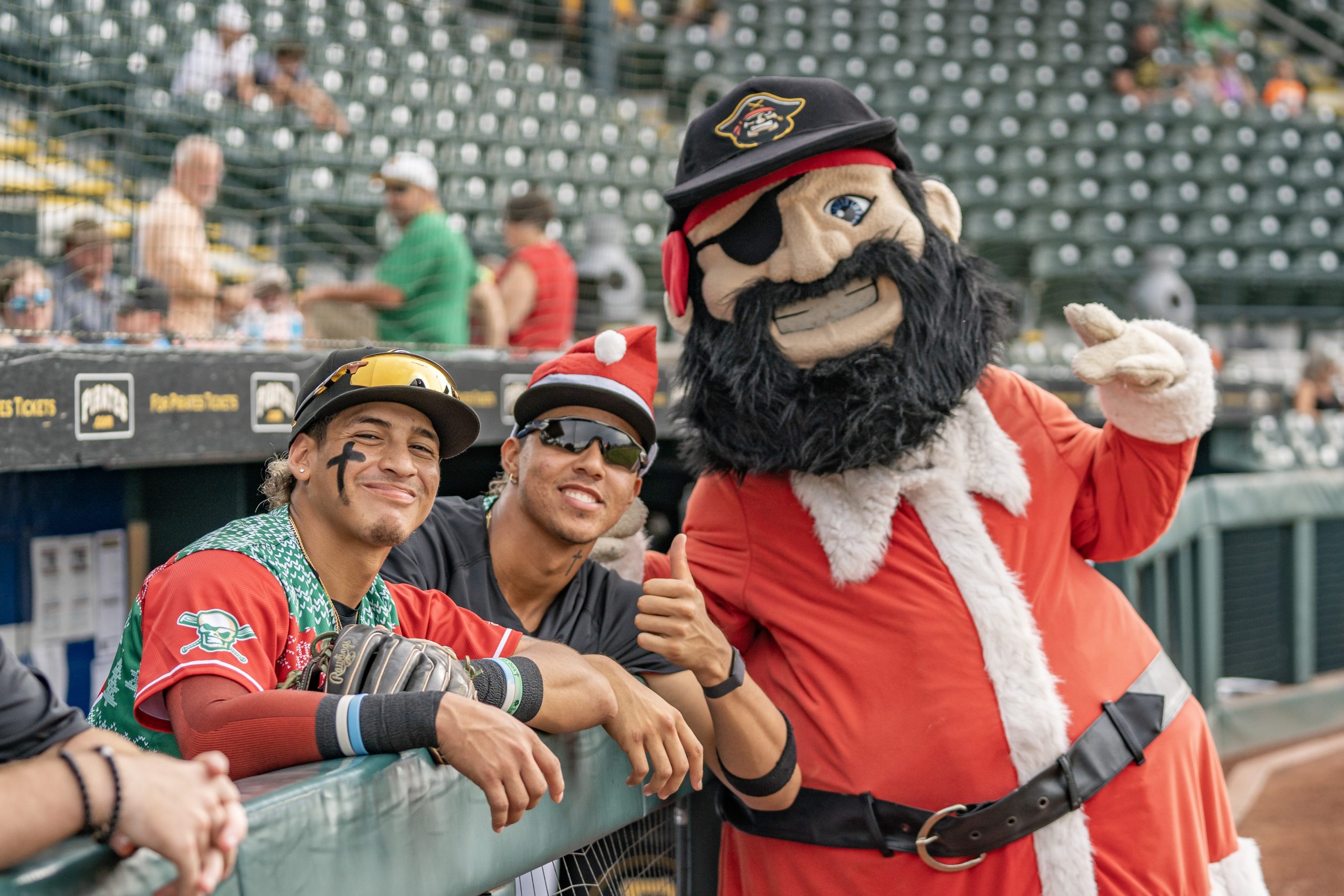Marty leaning against the bullpen fencing taking photo with two smiling players