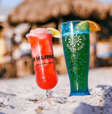 two brightly colored drinks with anna maria island beach cafe logos on them in the sand
