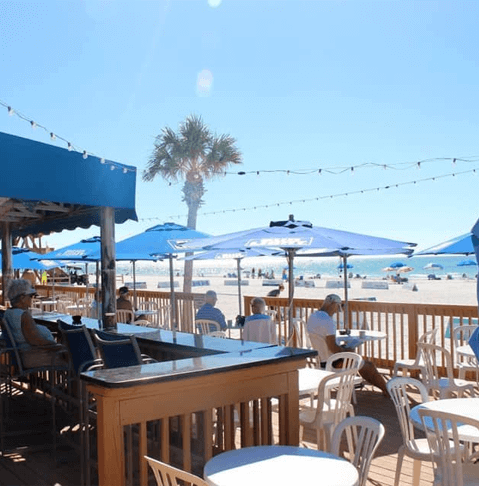blue umbrellas and white chairs and tables outside at Coquina Beach Cafe
