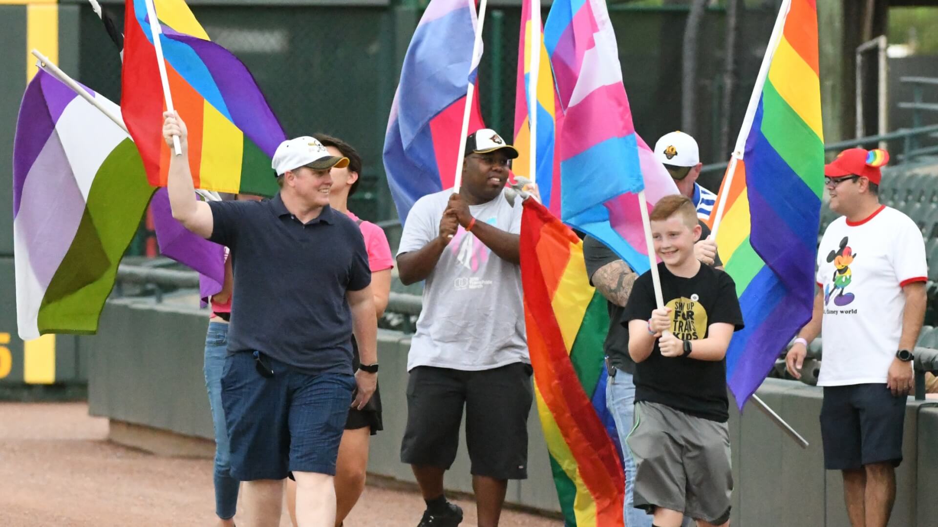 fans at a bradenton marauders game holding various pride flags