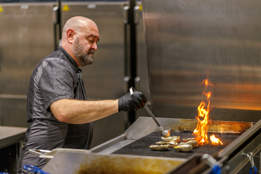 Chef Parker in the kitchen grilling oysters over a large flame