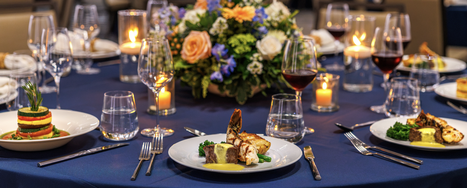 plated dinner with lobster and steak on a table dressed with floral arrangements